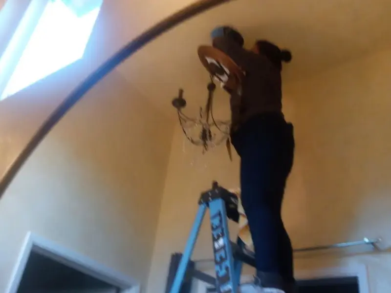 Electrician installing a chandelier in a Leesylvania residence